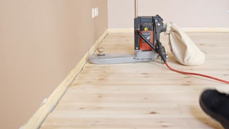 worker turns on floor sanding machine to start restoration work