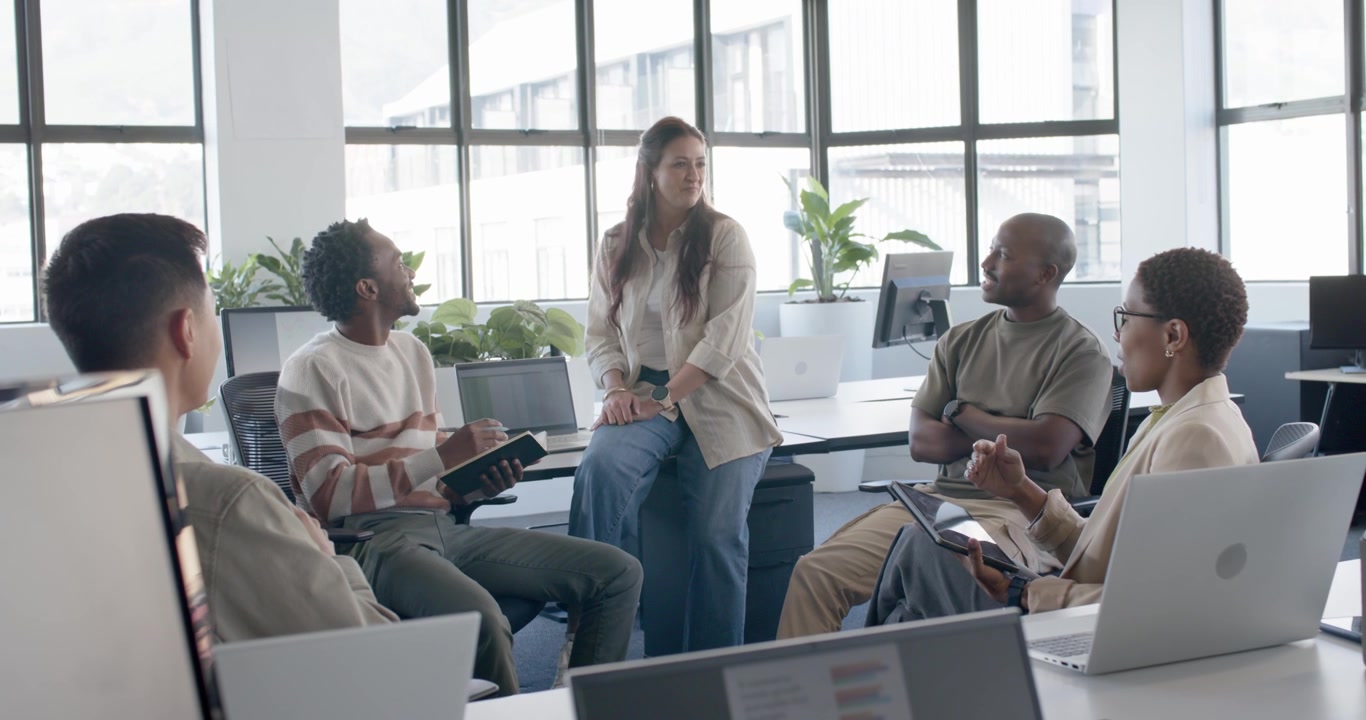 Diverse casual team reacting to notebook flip for review, tablet user showing mockup at office