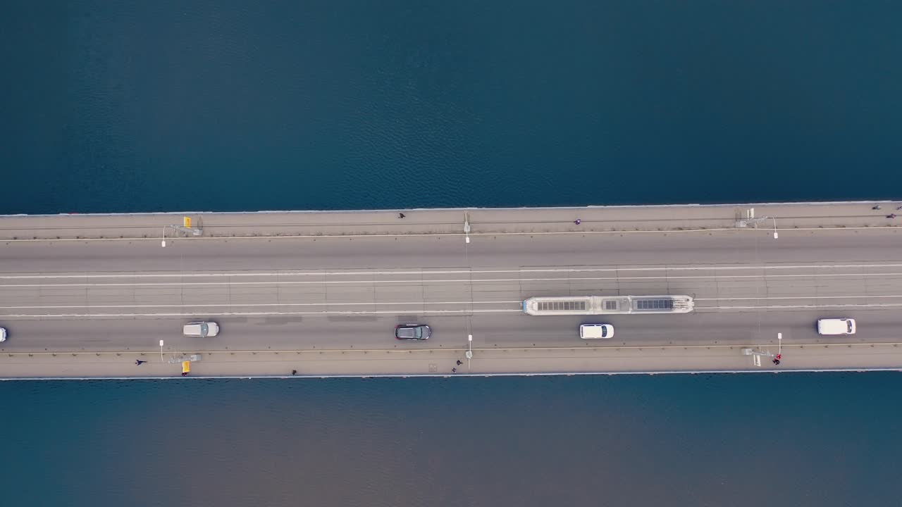 Aerial shot bridge with tram, cars moving. Drone flying over bridge with river, transport on a highway