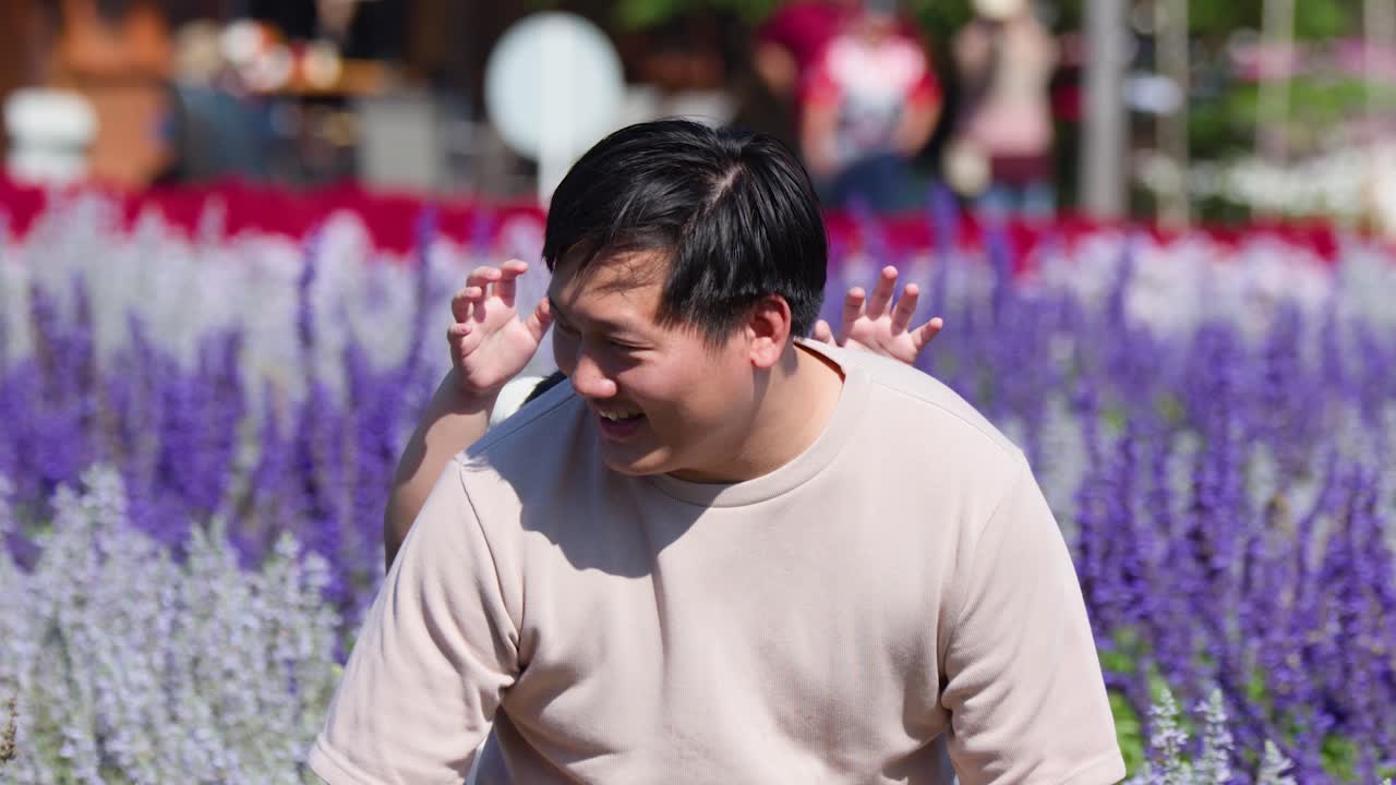Smiling father carries young daughter on piggyback through sunny purple flower garden