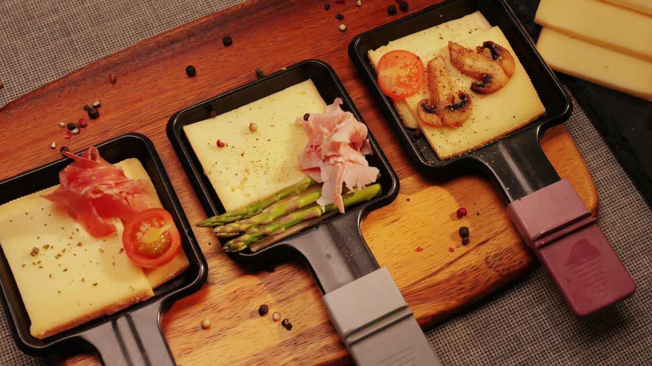 Traditional Swiss melted raclette cheese, hot melted French dish, family cooking dinner with Spanish style tapas ingredients and grill.