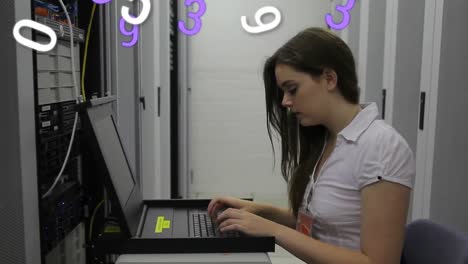 Animation-of-numbers-changing-over-woman-using-laptop-in-computer-server-tech-room