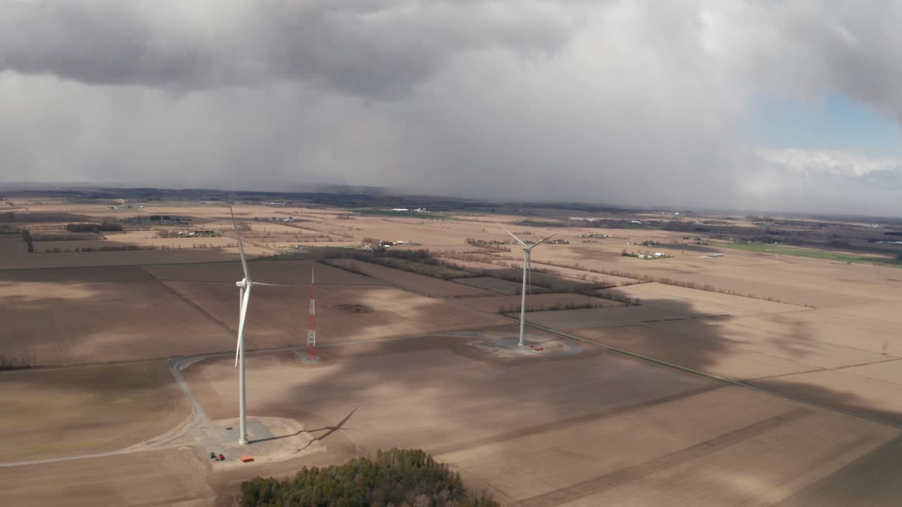 dos turbinas eólicas se elevan en medio de los campos de los agricultores
