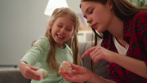 teenage girl and little sister compare vivid easter eggs