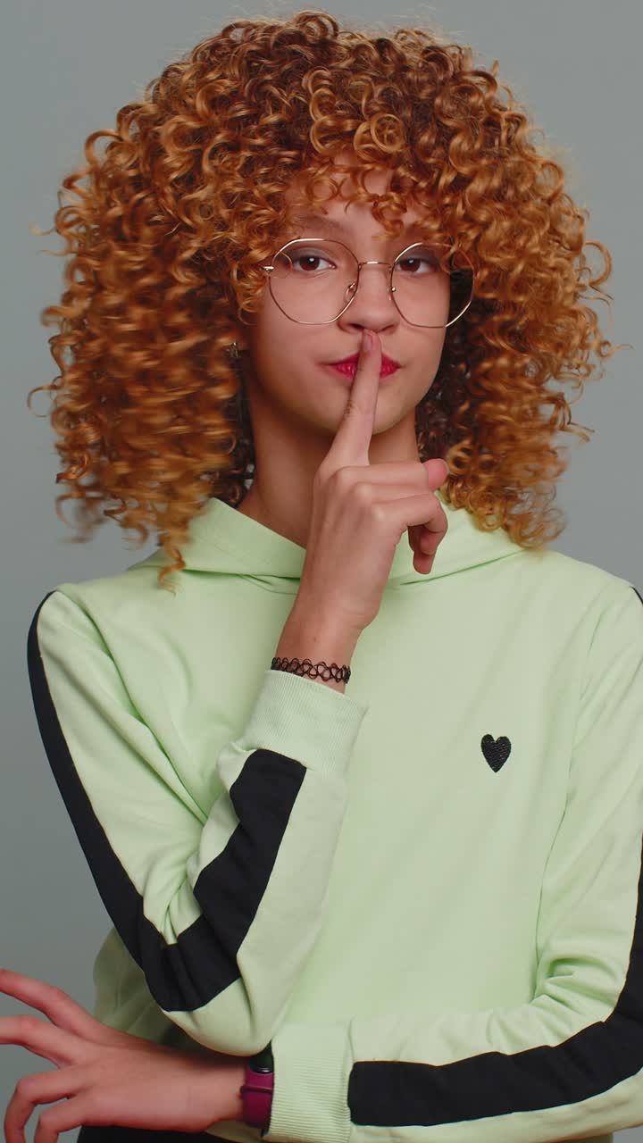 Teenager child girl presses finger to lips makes silence hush sign do not tells gossip secret quiet