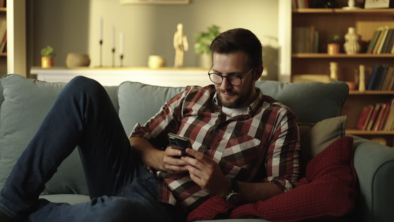 Man relaxing on a couch while using a smartphone