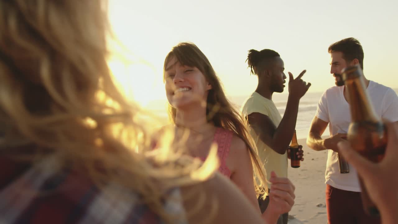 Young adult friends drinking on a beach at sunset 4k