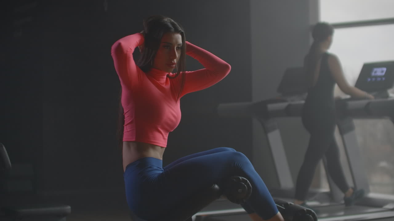 The woman pumps oblique muscles of the abdomen. She bends and unbends the torso and leads it to the side.