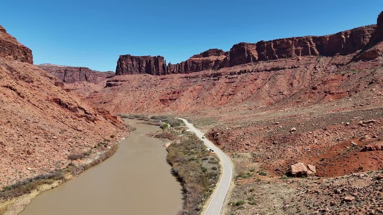 Car Driving Down Road Next to River Surrounded by Tall Red Cliffs, Colorado River, Moab Utah, Highway 128, Upper Colorado River Scenic Byway