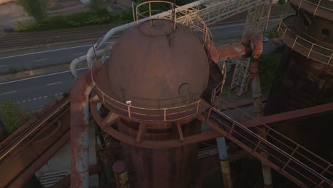 blast furnace with large metal pipes, with the adjacent road in the background.