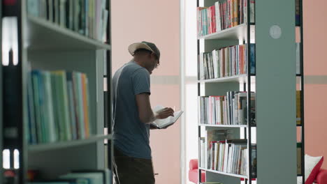 college student stands between library shelves near window light, flipping through book with focused posture, pages turning slowly, quiet study mood, research mindset, modern interior with soft glow