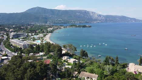 dolly in aerial flight over dassia bay and beach during daytime, overlooking the sea, coastline, and mountains in corfu, greece