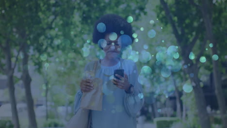 woman walking urban pathway holding bag looking at smartphone, showing floating tech graphs