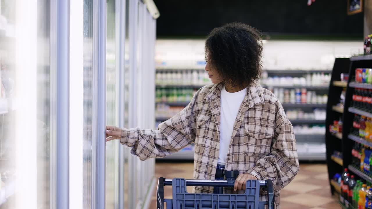 카트 를 가진 여자 가 슈퍼마켓 에서 냉장고 문 을 열다