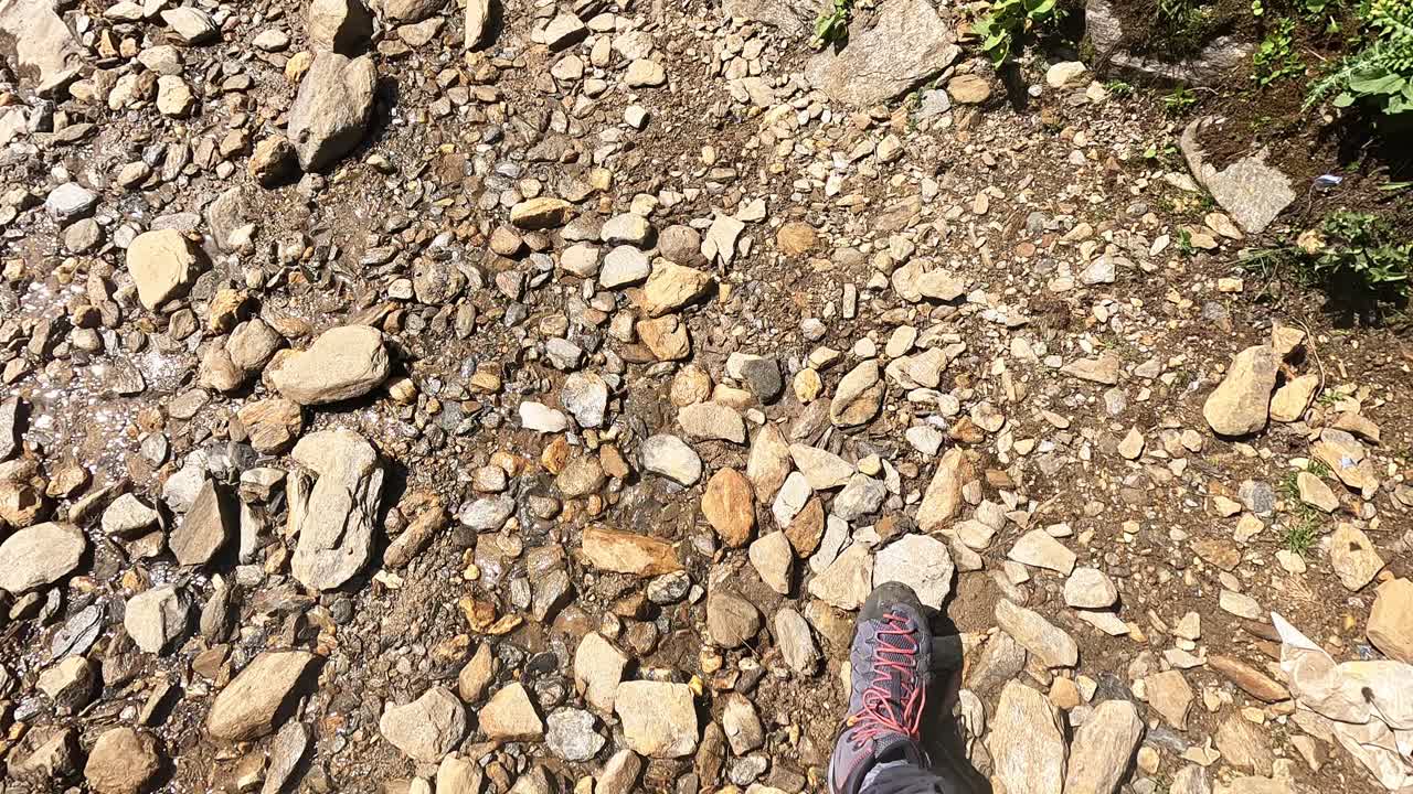 vista de un excursionista que baja mientras cruza un río en las montañas