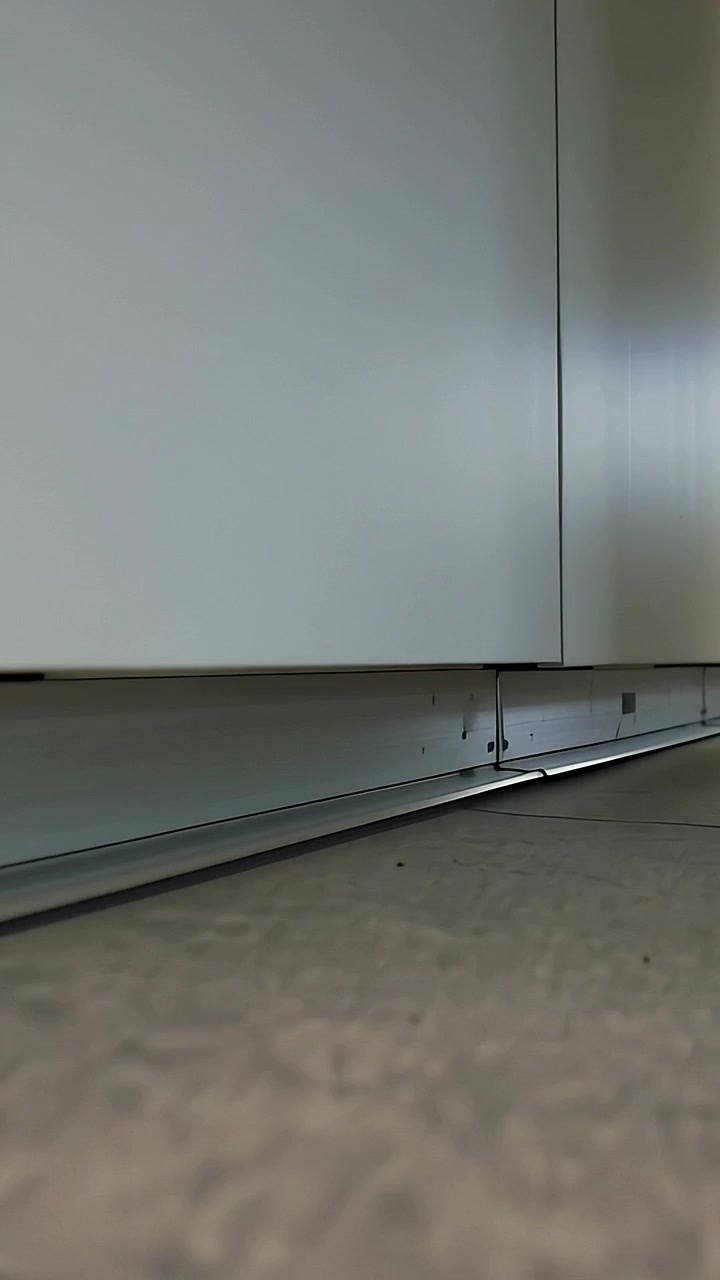 Vertical video: Starting left panning low camera inspecting cabinets in kitchen showing skirting