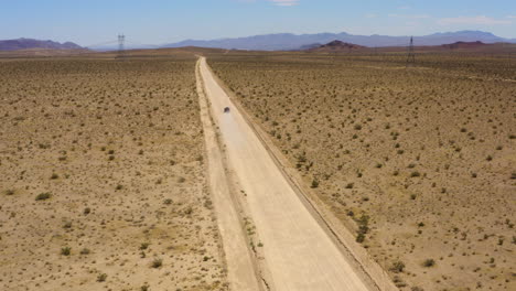 SUV-Negro-Acelera-Por-Un-Camino-Recto-Del-Desierto-Dejando-Una-Nube-De-Polvo-Detrás