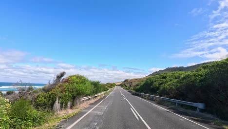 a serene drive along the great ocean road with coastal views, lush greenery, and clear blue skies captured in vibrant daylight