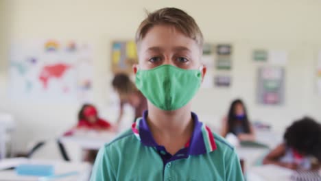 Portrait-of-boy-wearing-face-mask-in-class-at-school