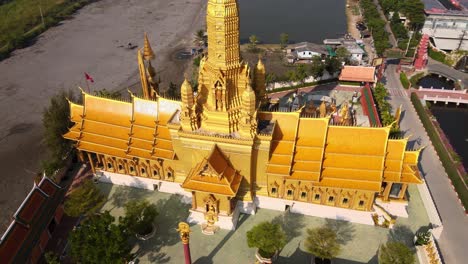 4k aerial close up of beautiful golden temple with the golden standing buddha statue in the ancient city park, muang boran, samut prakan province