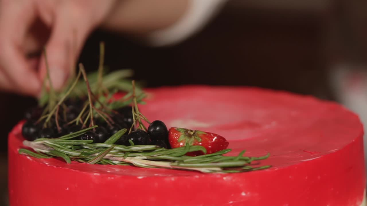 decorando un pastel de terciopelo rojo con bayas y romero