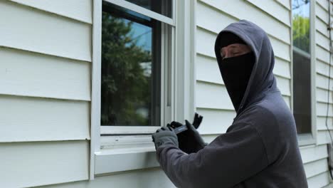 los ladrones abren una ventana con una palanca y comienzan a subir a una casa