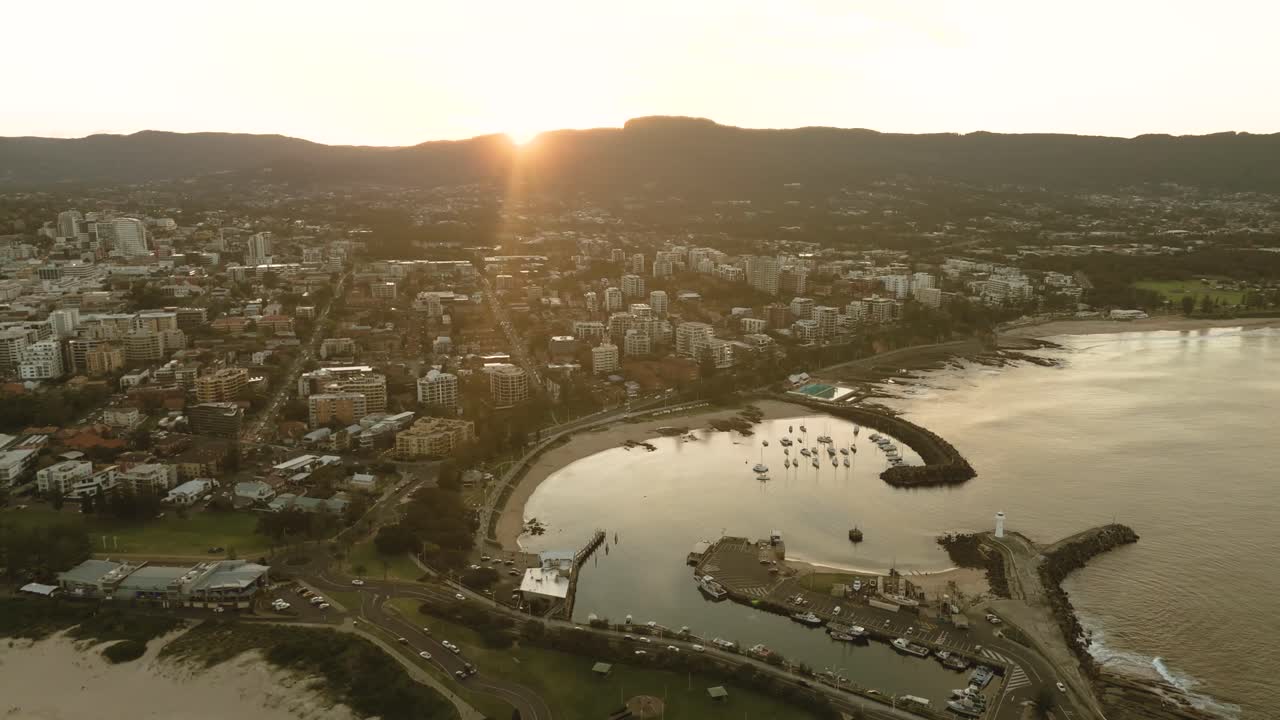 Aerial view of Wollongong’s coastal city during sunset, capturing the stunning landscape and golden light reflecting on the ocean