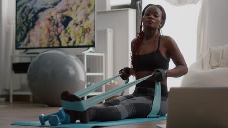 fit black woman in sportswear looking at online workout on laptop