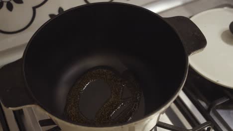 el chef agrega aceite a la olla profunda, calentándose en una estufa de gas