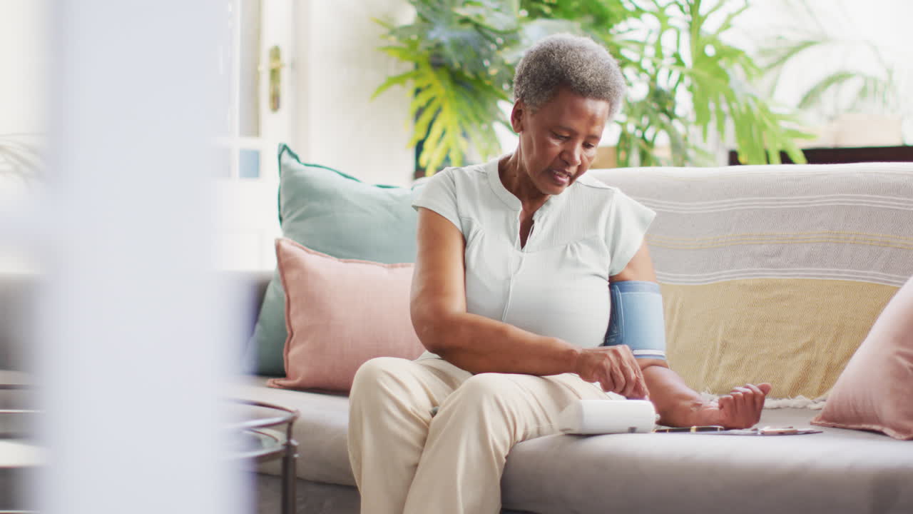 Senior african american woman measuring pressure and taking notes at home