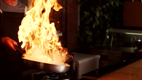 Cook-preparing-food-in-frying-pan-with-fire