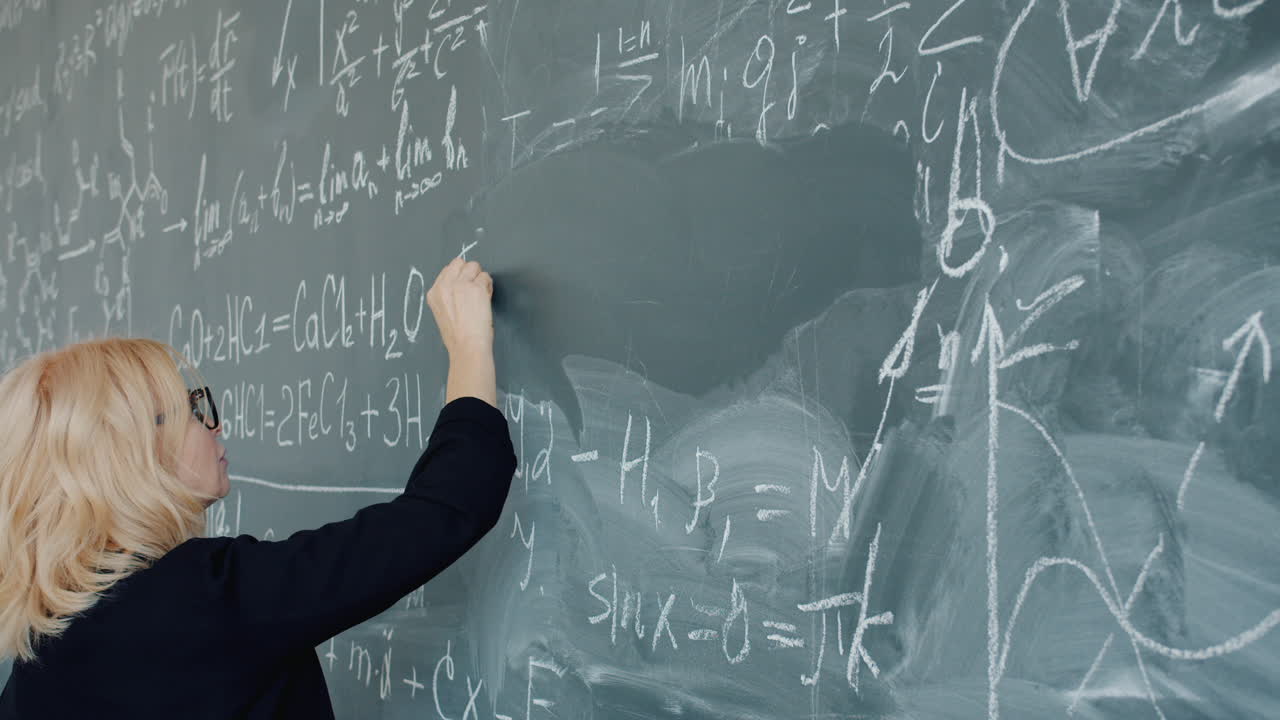 Teacher Writing Equations on Chalkboard