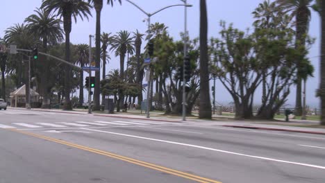 a car travels along a seaside street in santa monica california as seen through the rear window at an angle