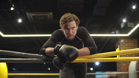 aggressive fit man leaning on ring ropes in sport club. boxer screaming at gym