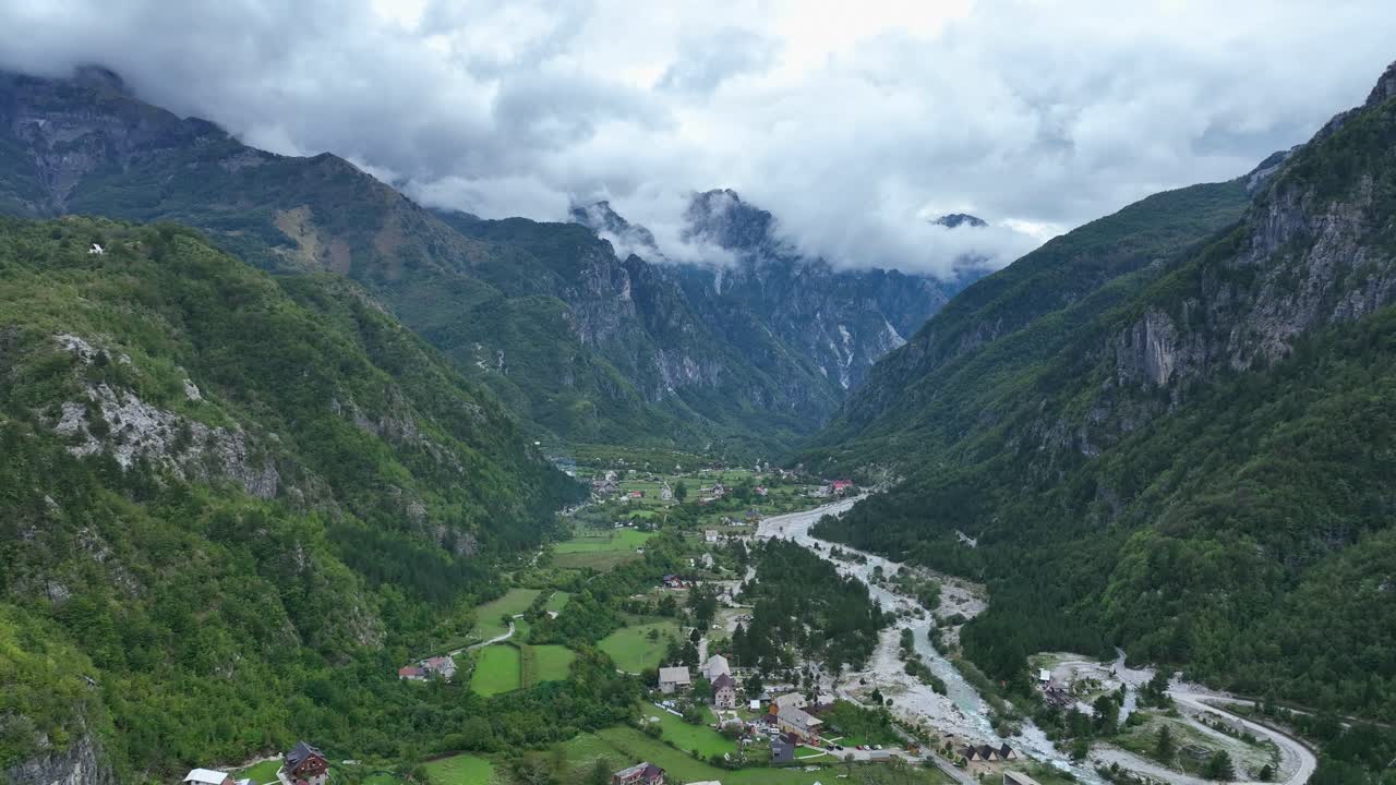 A valley in theth, albania, surrounded by lush mountains and mist, aerial view