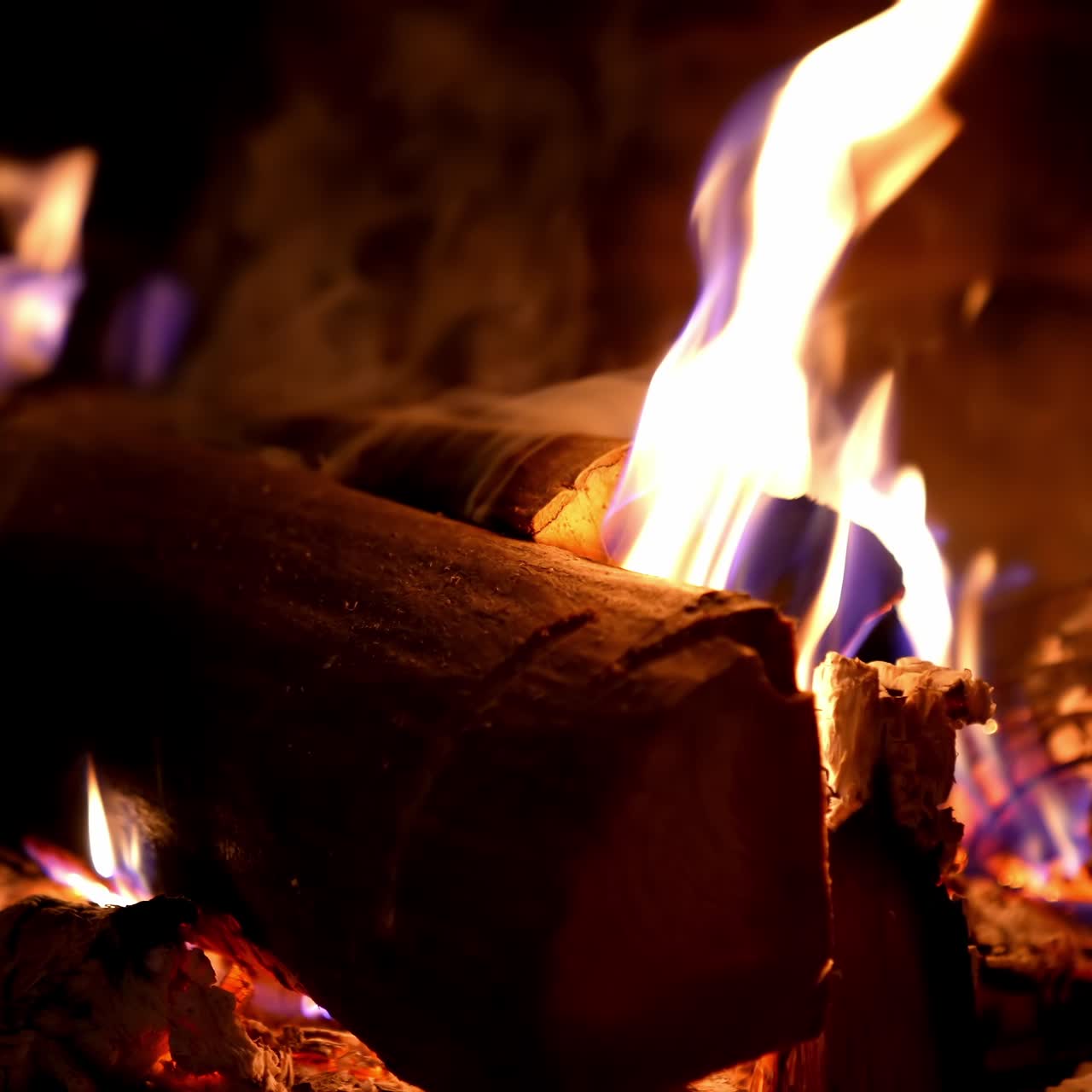 Firewood burning background. Fire flame and smoke on wooden logs in fireplace. Warmth and relaxation near the fireplace at winter season. Close-up