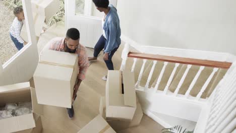 happy african american couple with son and daughter bringing boxes into house, slow motion