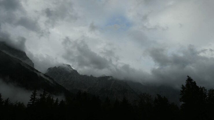 Time lapse of clouds over mountain peak, dramatic stormy sky, forest in foreground, Ojstrica peak in Kamnisko Savinjske Alpe, Logarska dolina, Slovenia, European Alps