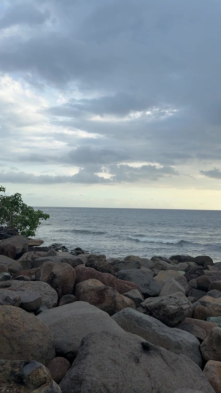 Onde che si infrangono dolcemente su una costa rocciosa sotto un cielo nuvoloso.