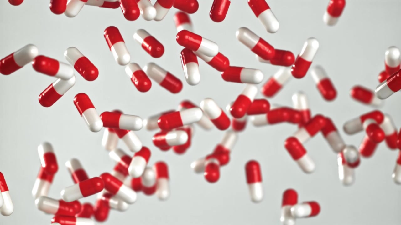 Capsule mediche rosse e bianche che cadono al rallentatore