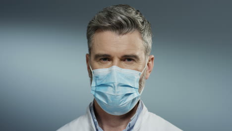 Portrait-Of-The-Young-Happy-Man-Physician-Taking-Off-Mask-From-His-Mouth-And-Smiling-Cheerfully