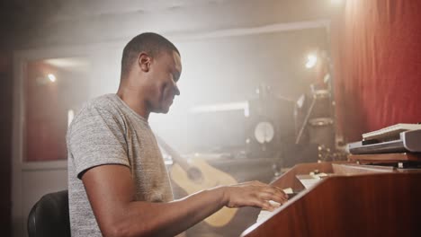 black man playing synthesizer in recording studio