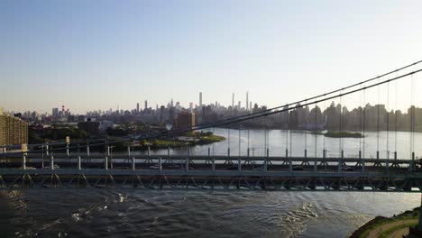 cars crossing nyc's triboro bridge into manhattan, east river with downtown skyline