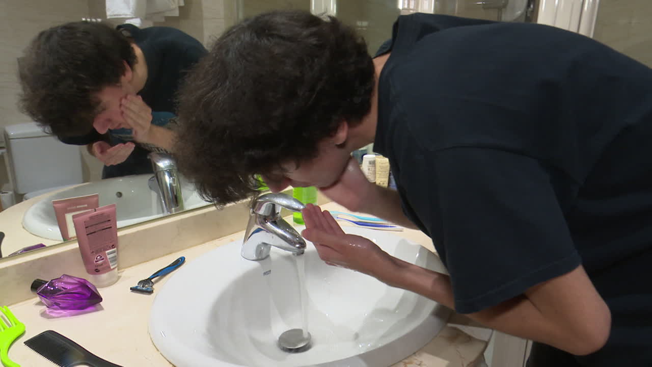 Teenager washing hands/face in a hotel bathroom