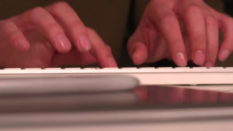 hands typing on a keyboard, glasses resting on the desk then put on