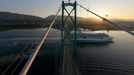 lions gate bridge crosses burrard inlet with cruise ship during golden hour in vancouver, bc, canada