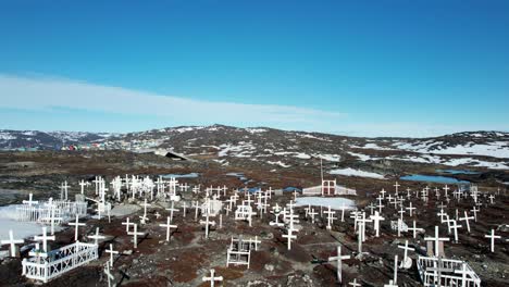 Rocky-terrain-of-Greenland-with-remote-cemetery,-aerial-fly-back-view