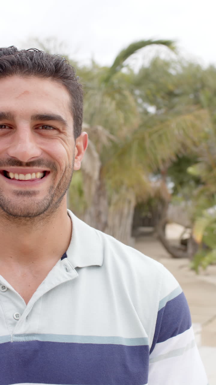 Vertical video of portrait of happy caucasian man at beach house