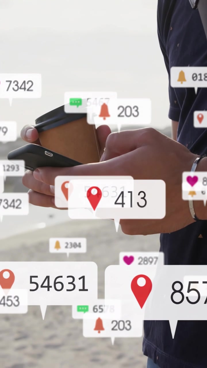 Vertical video: Man tapping phone on beach, checking social media while badges growing over phone