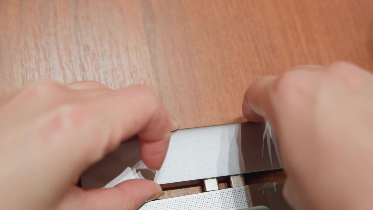 Hub en aluminium s'alignant avec les ports d'ordinateur portable, mains de technicien insérant soigneusement l'adaptateur multiport dans le bord de l'ordinateur portable sur l'établi, alignement précis, inspection et calibration pendant le flux de travail de réparation